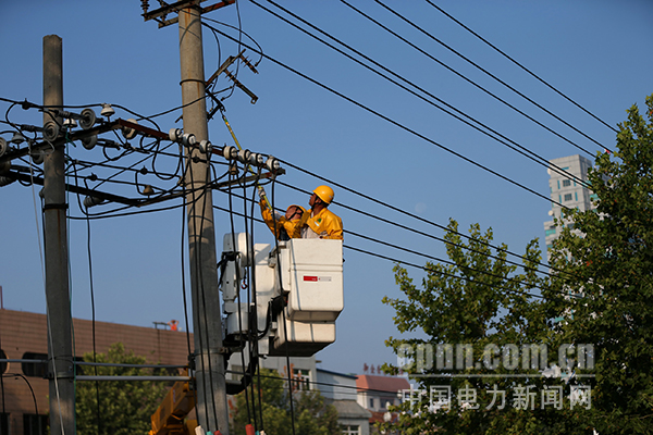 图为带电检修人员冒高温在10kV城南118线路34#杆带电更换隔离刀闸。